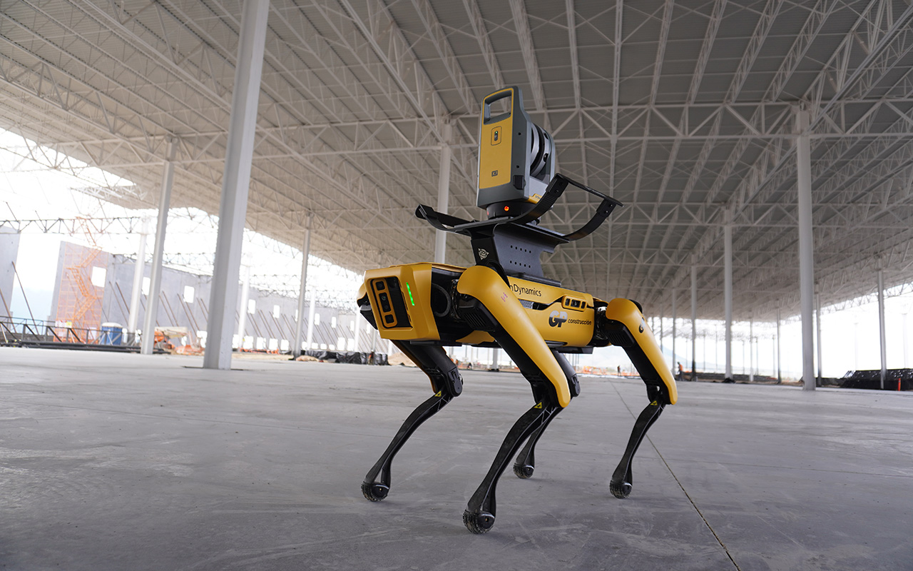 Robot cuadrúpedo amarillo con escáner recorre el interior de una nave con columnas.