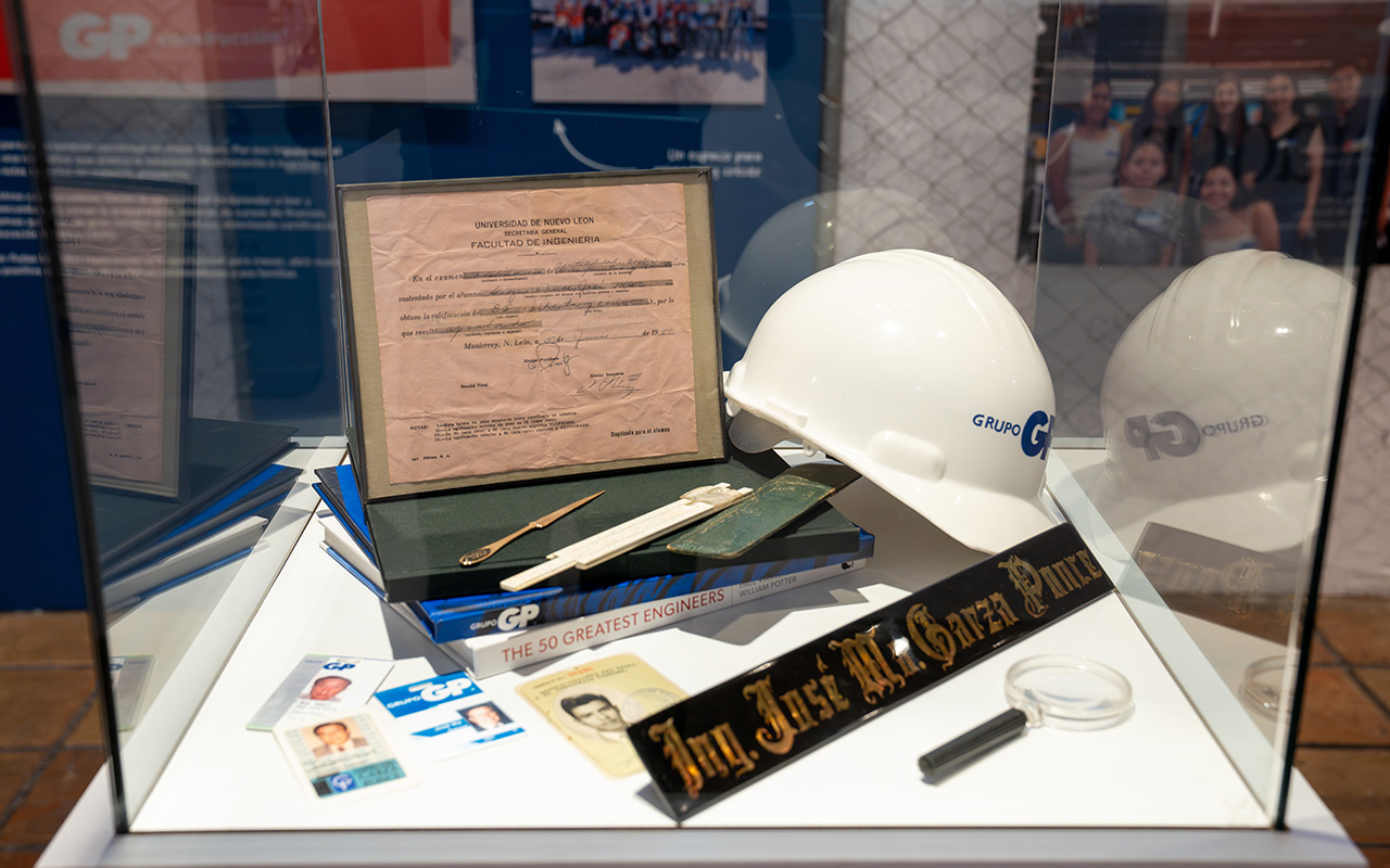 Vitrina con casco de Grupo GP, título y placa del ingeniero José Ma. Garza Ponce.
