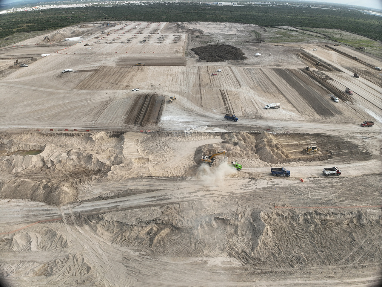 Vista aérea del movimiento de tierras, con camiones y excavadoras en el predio.