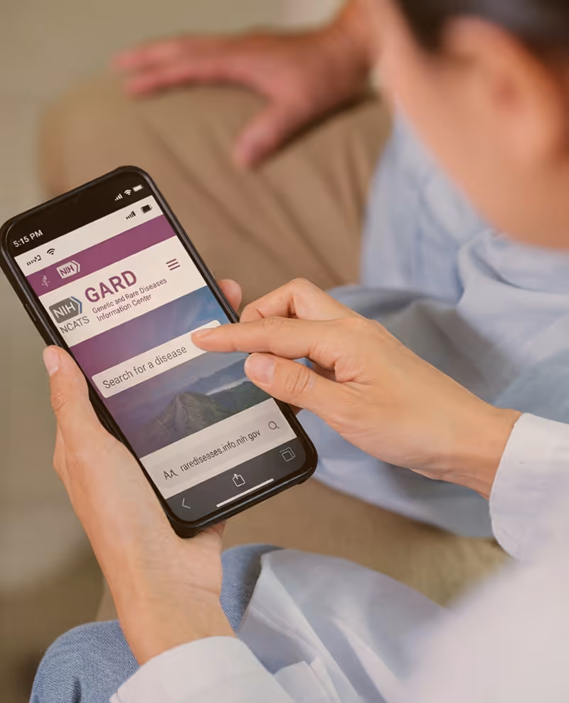 Person using NIH GARD website on phone to search for genetic and rare diseases.