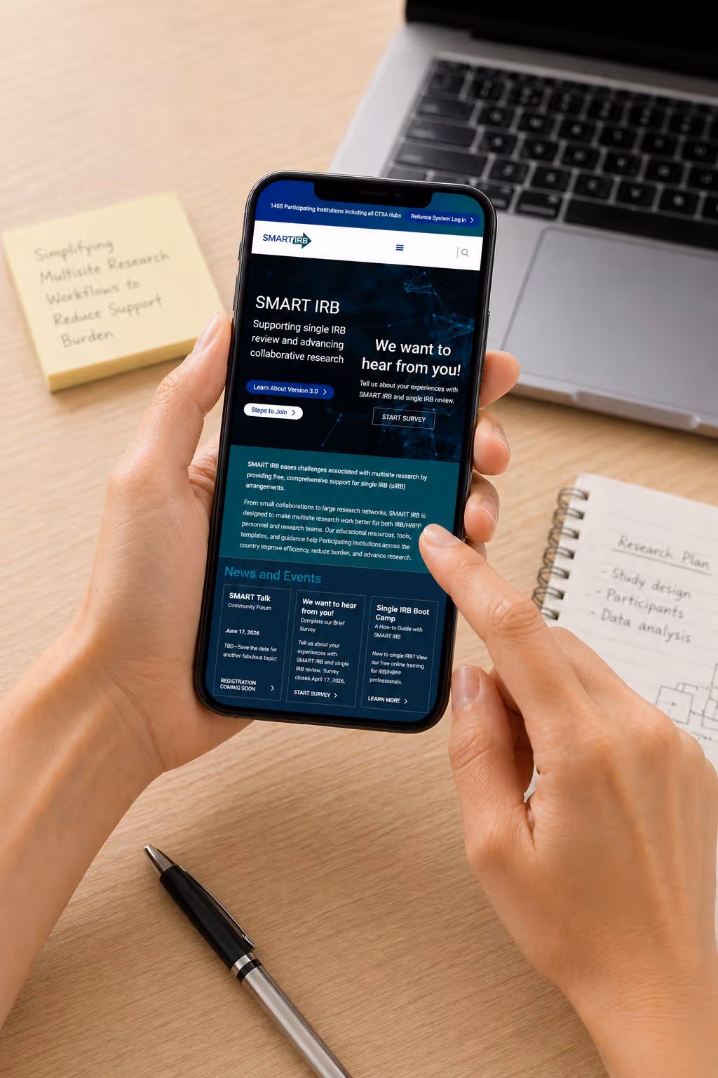 Person holding phone displaying SMART IRB webpage on research support and events.