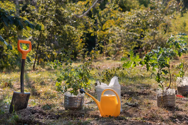 Garden scene with a shovel, orange watering can, white plastic container, and small plants in recycled plastic bottles.
