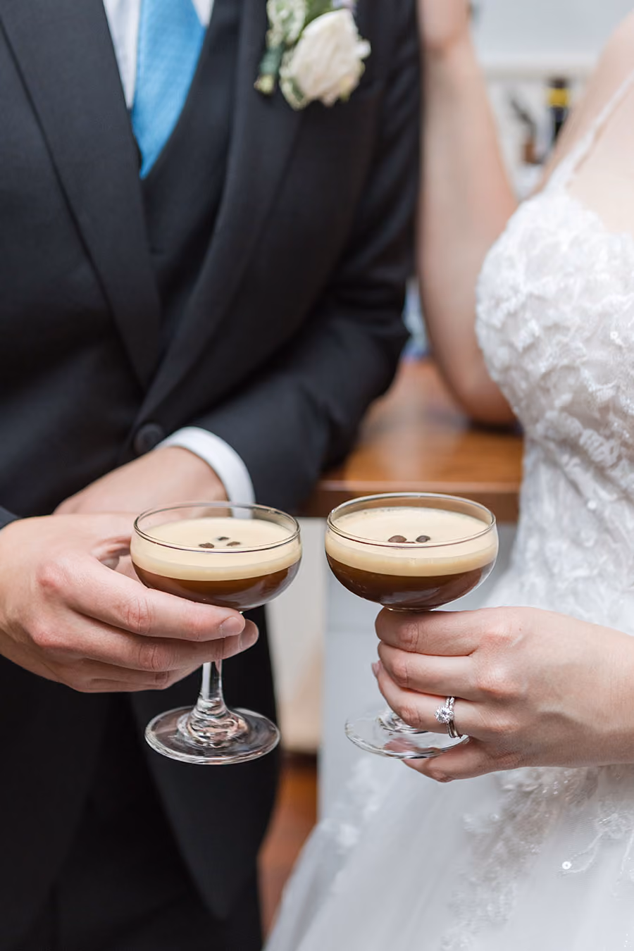 Bride and groom in wedding attire holding espresso martini cocktails with coffee bean garnish.