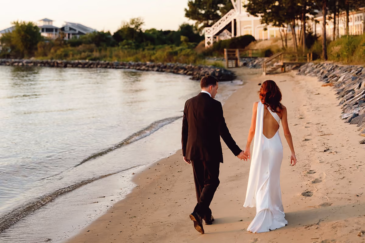 Newlyweds walking hand in hand along the beach at the Chesapeake Bay Beach Club