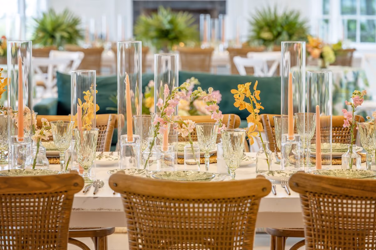 Elegant rehearsal dinner tablescape with taper candles, orchids and woven chairs at Chesapeake Bay Beach Club