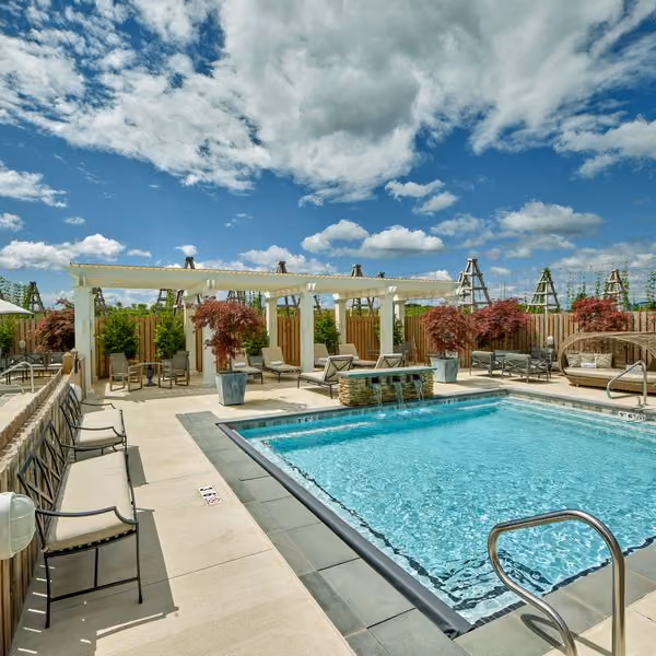 Outdoor pool deck with a pergola, lounge chairs and dramatic sky at The Inn's Splash Garden