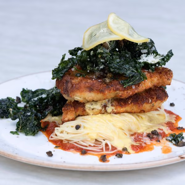 Plated chicken parmesan stack with crispy kale over angel hair pasta at Knoxie's Table