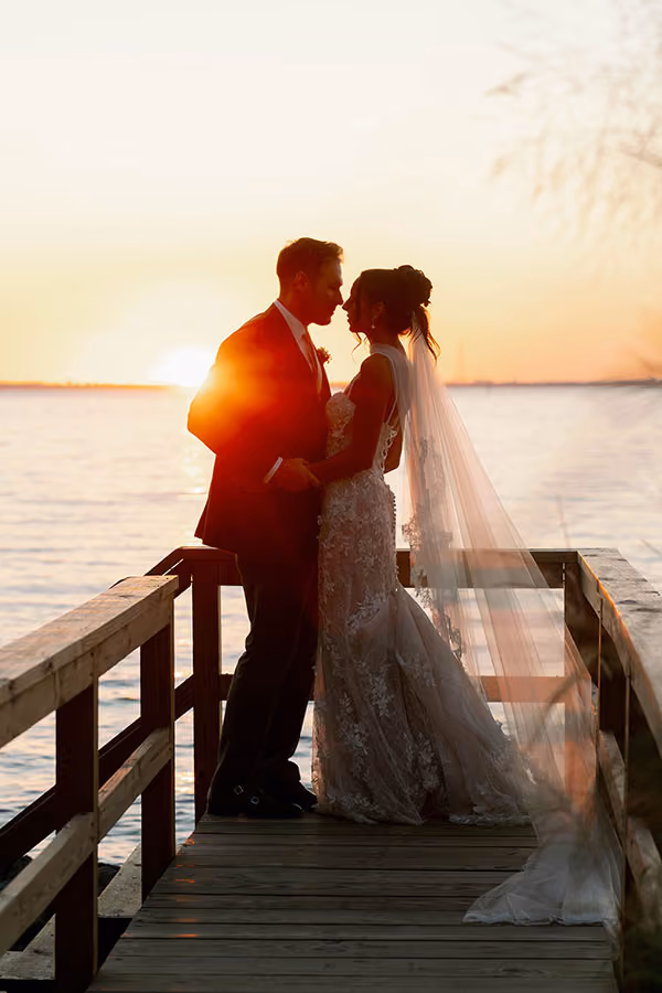 Bride and groom sharing a moment on a waterfront dock at sunset at Chesapeake Bay Beach Club