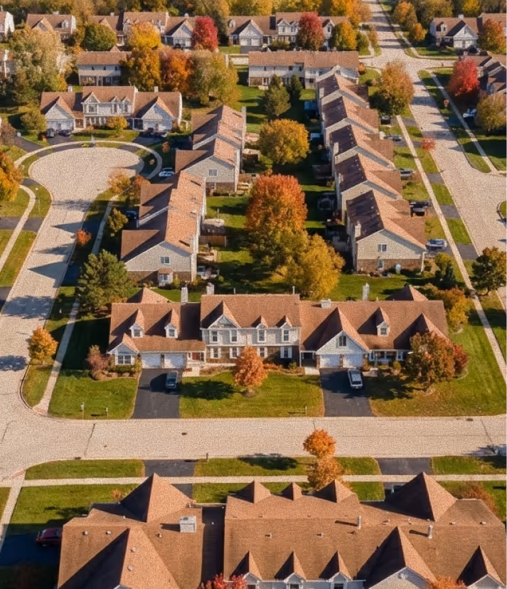 Aerial view of a suburban neighborhood with townhouses, trees in autumn colors, and streets.