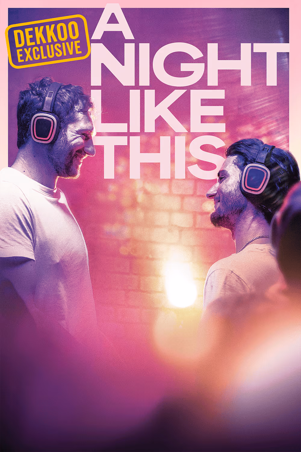 Promotional artwork for the Dekkoo Exclusive A Night Like This, featuring two men wearing headphones and facing each other in a nightclub bathed in pink and purple light.