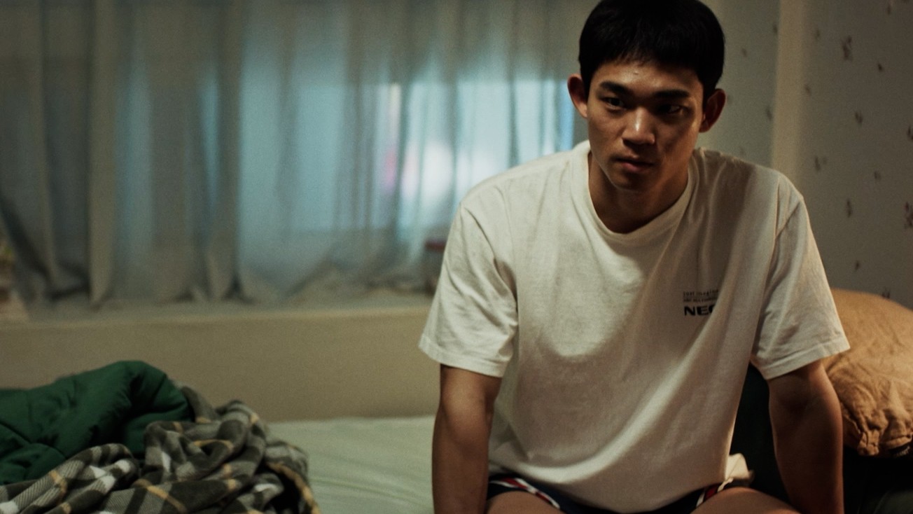Cheol-jun sits alone on the edge of a bed, reflecting on his new life in Seoul in the Korean LGBTQ drama 3670.