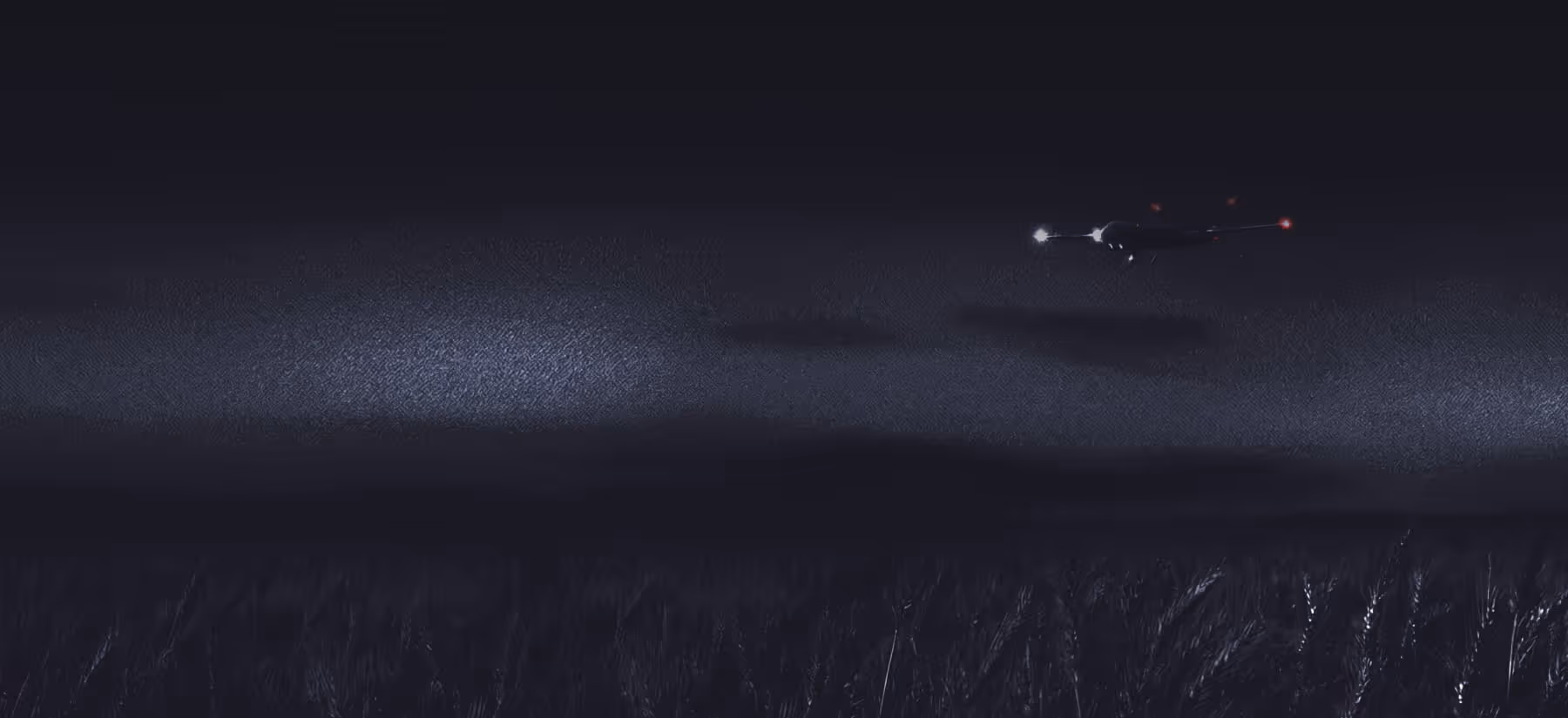 Drone flying at night over a dark field with navigation lights on.