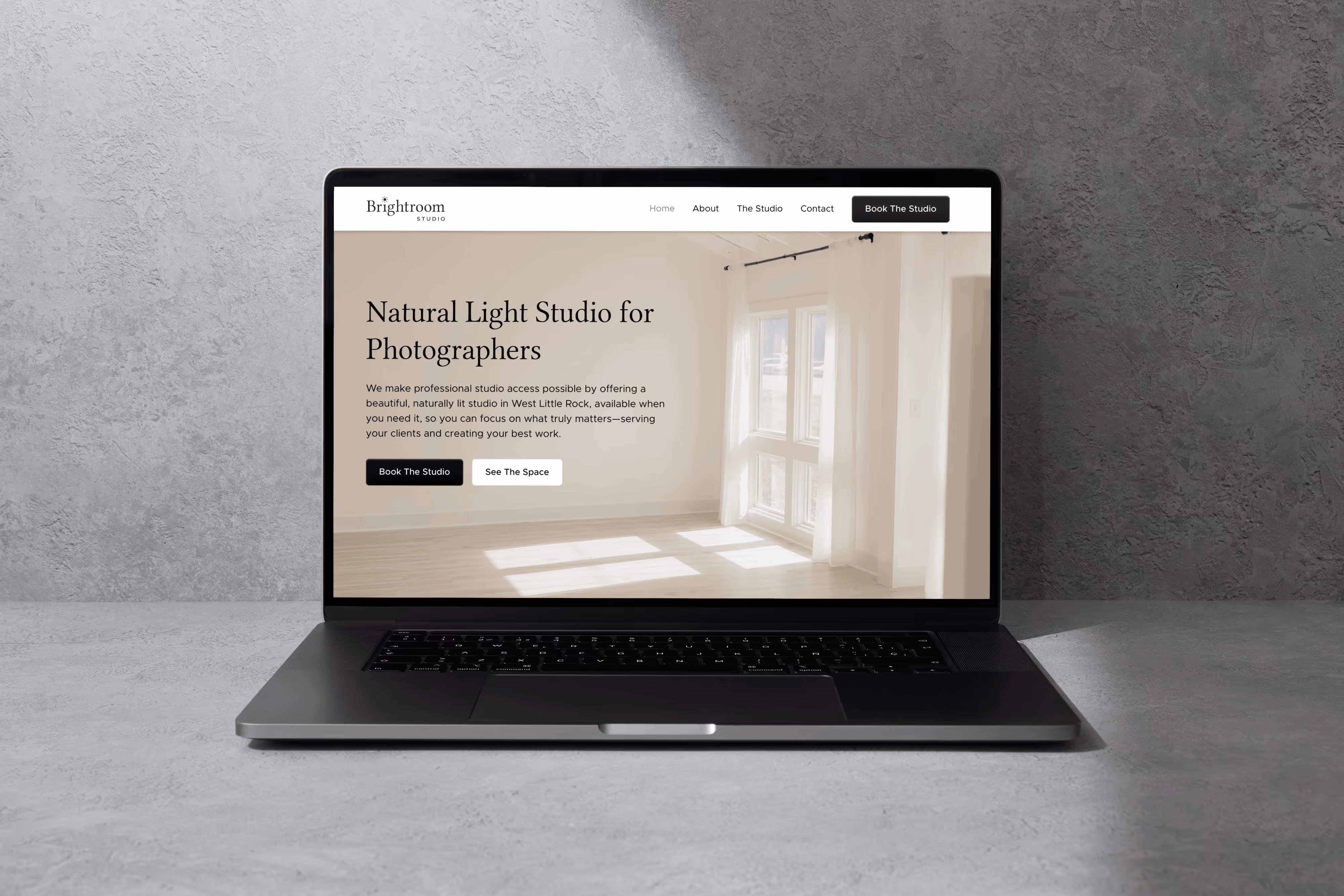 Laptop displaying Brightroom Studio website with a bright, empty photography studio featuring large windows and natural light.