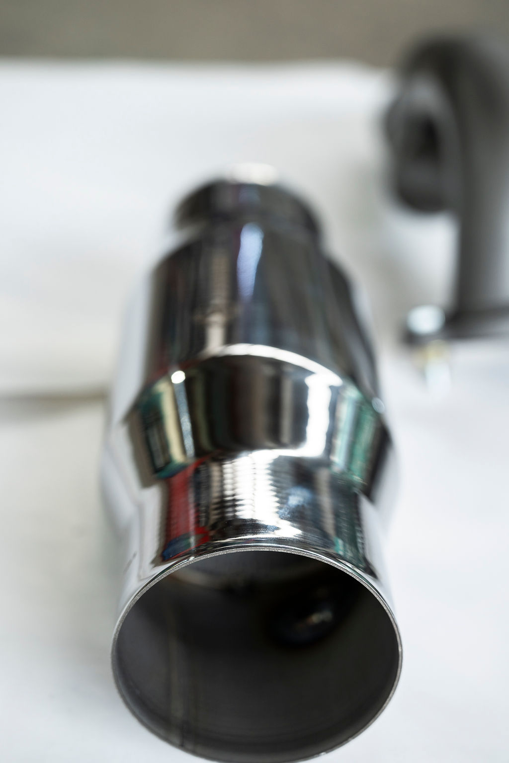 Close-up of a reflective stainless steel cylindrical exhaust pipe.