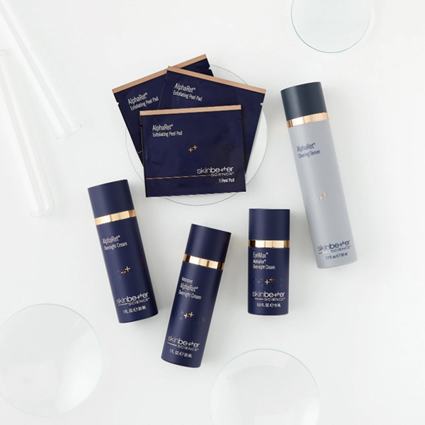 Skincare products including exfoliating peel pads, cleansing serum, and various creams on a white surface.