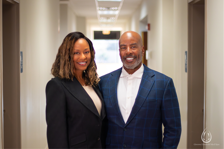 Smiling woman and man in professional attire standing together in a hallway.