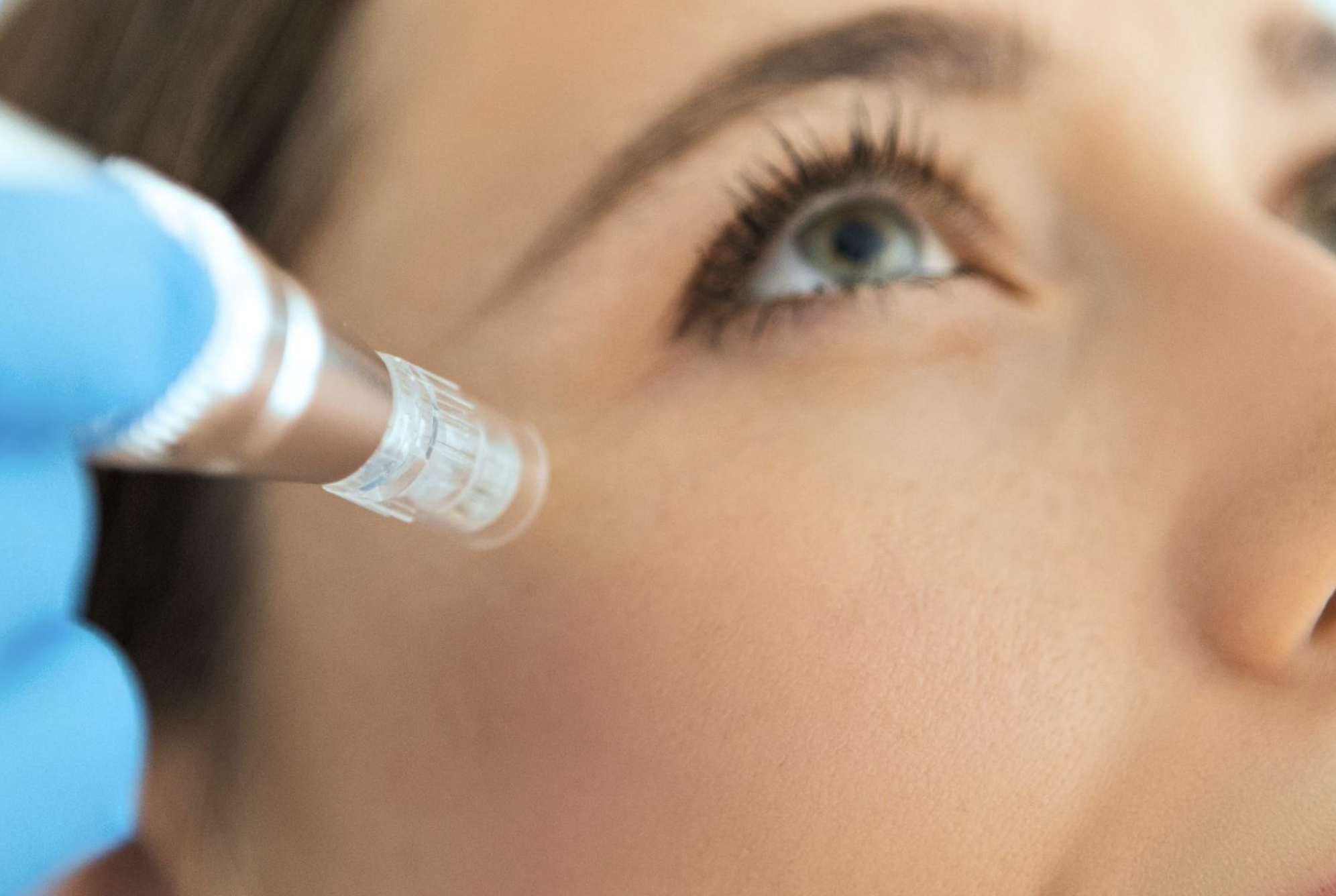 Close-up of a person receiving an eyebrow grooming treatment by a professional wearing black gloves.