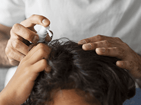 Man smiling while unpacking a small white box from a cardboard box in a warmly lit living room.