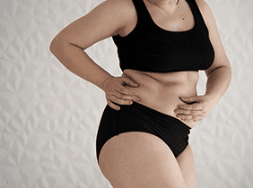 Man smiling while unpacking a small white box from a cardboard box in a warmly lit living room.