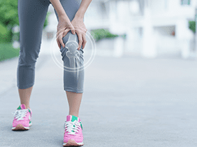 Man smiling while unpacking a small white box from a cardboard box in a warmly lit living room.