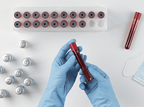 Man smiling while unpacking a small white box from a cardboard box in a warmly lit living room.