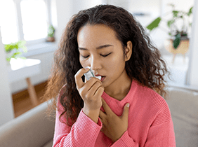 Man smiling while unpacking a small white box from a cardboard box in a warmly lit living room.