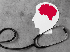 Man smiling while unpacking a small white box from a cardboard box in a warmly lit living room.