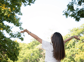 Man smiling while unpacking a small white box from a cardboard box in a warmly lit living room.