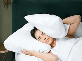 Man smiling while unpacking a small white box from a cardboard box in a warmly lit living room.