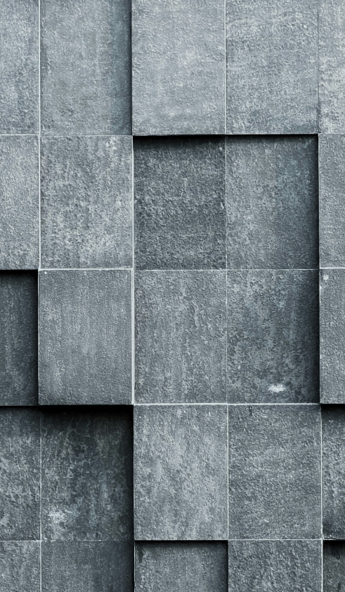 Gray textured stone tiles arranged in a staggered, overlapping pattern creating a three-dimensional wall effect.