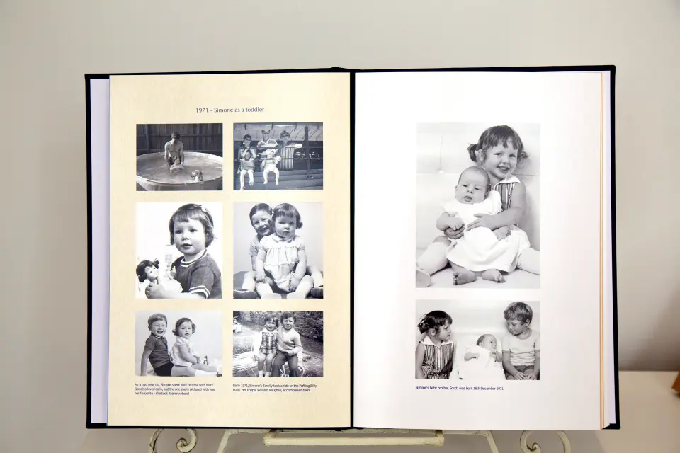 Open photo book featuring black-and-white childhood photos from 1971, showing a toddler Simone with family and baby brother Scott.