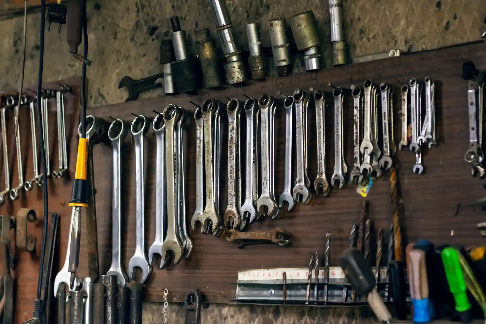 A wooden board with various wrenches and socket tools neatly arranged hanging on it. 