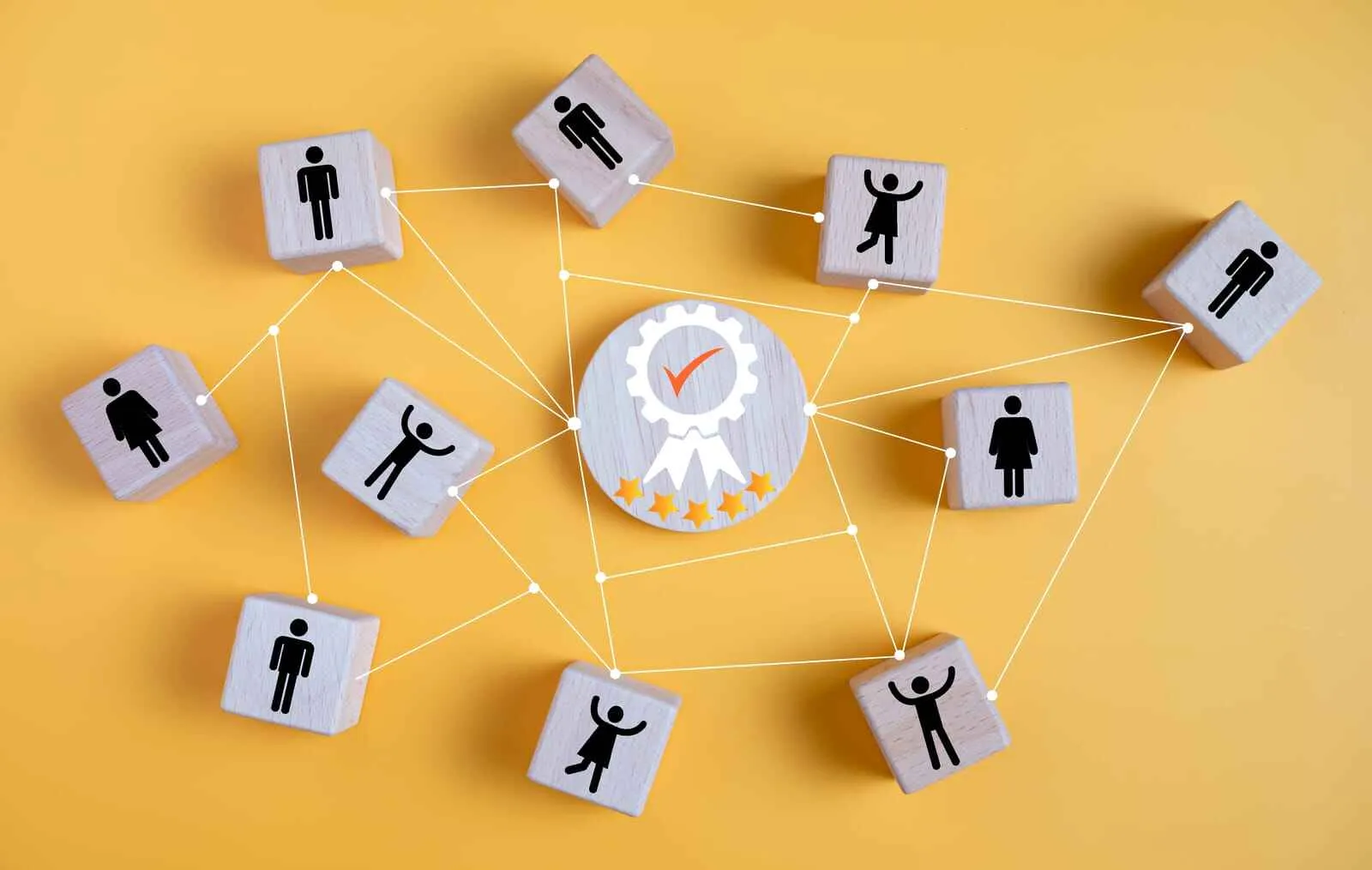 Bloques de madera con iconos humanos interconectados que rodean un bloque central con un símbolo de experiencia positiva para el usuario.