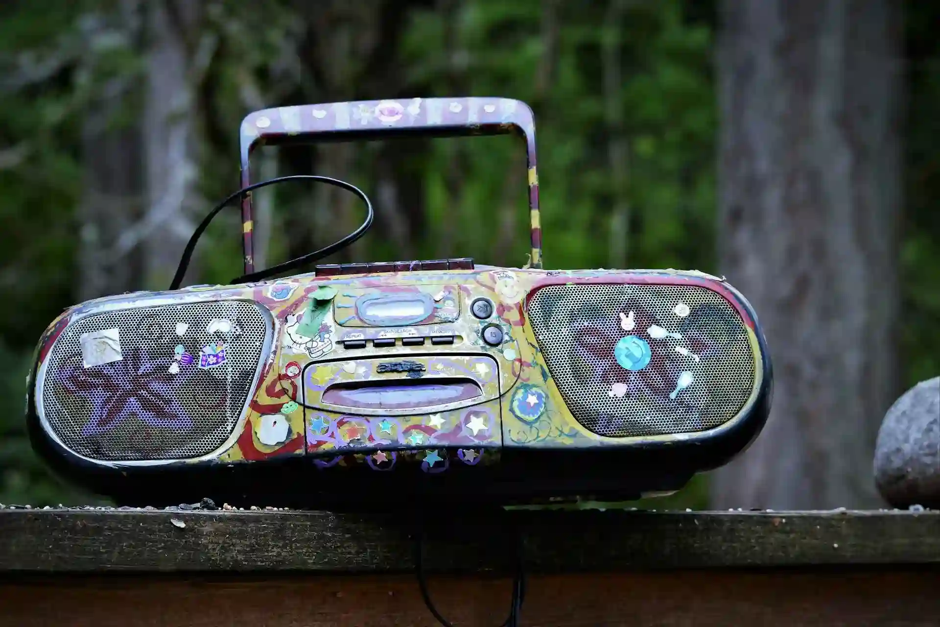 Un colorido radiocasete con asa sobre una superficie de madera al aire libre.