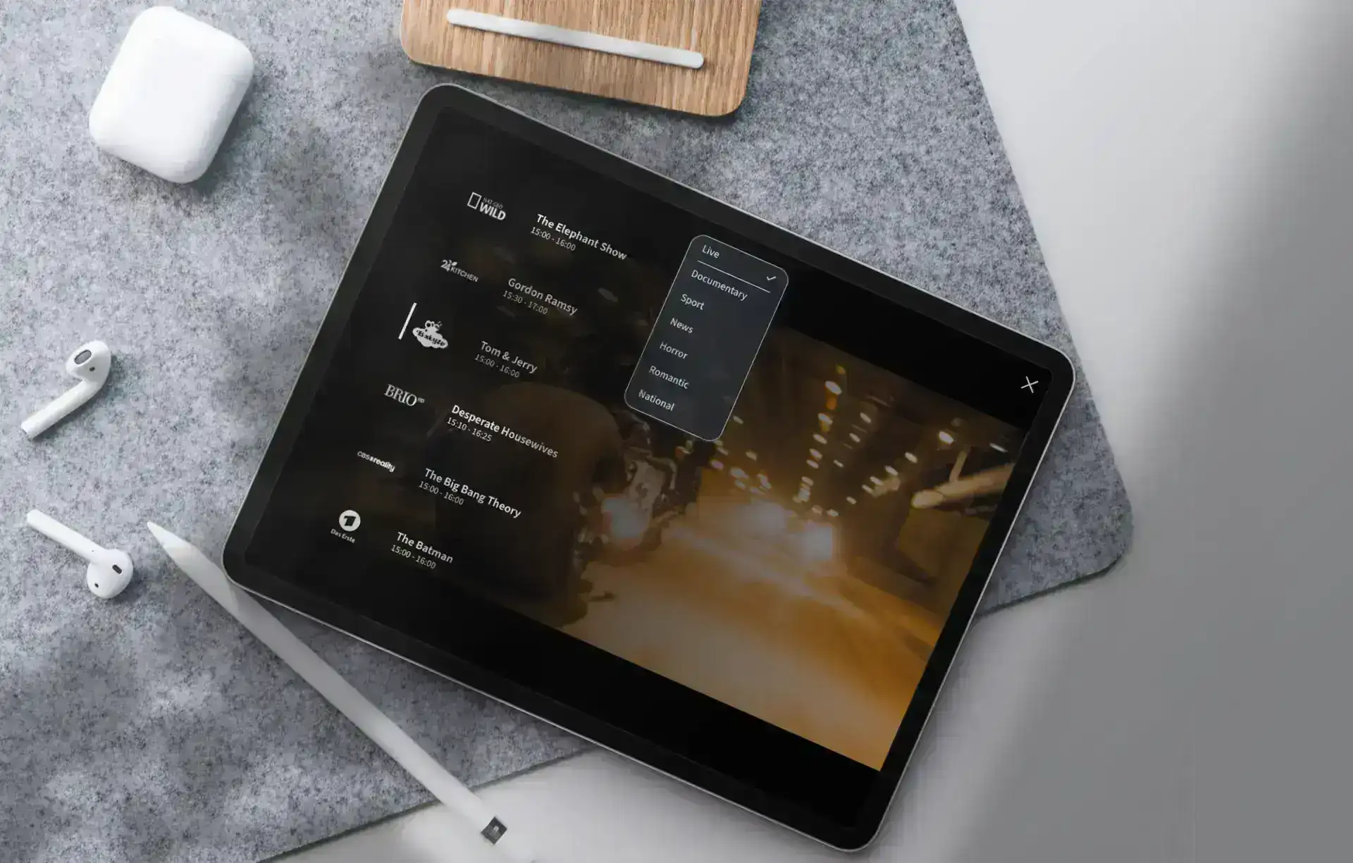 Una tableta que muestra un menú en una superficie gris junto a unos auriculares inalámbricos y un lápiz óptico.