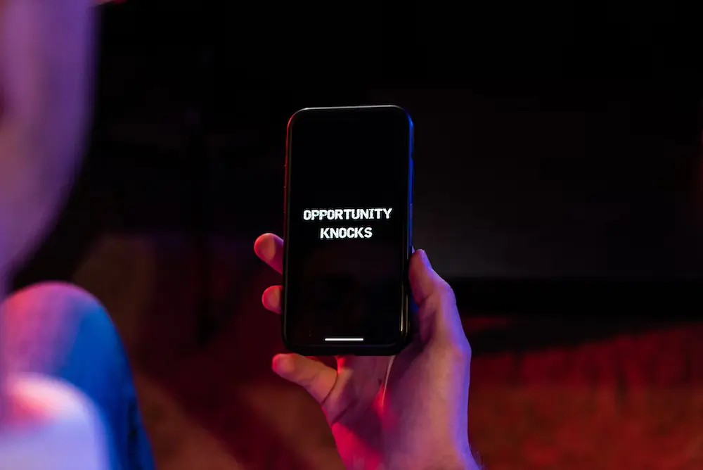 An image of a person holding a black iphone 4 with a text "opportunity knocks".