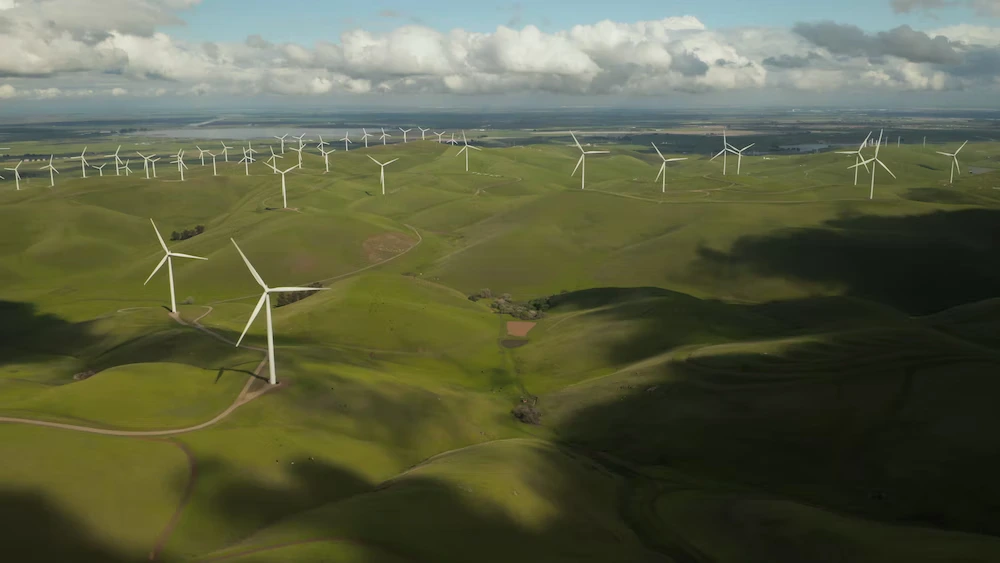 A image of many white windmills on green hilltops during daytime.