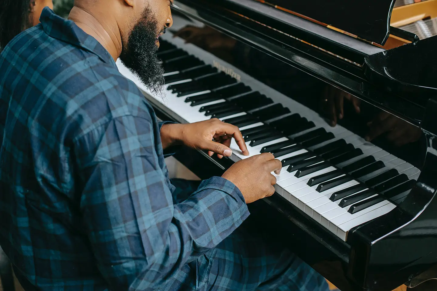 Hombre africano tocando las teclas de un piano que representa a un teclista