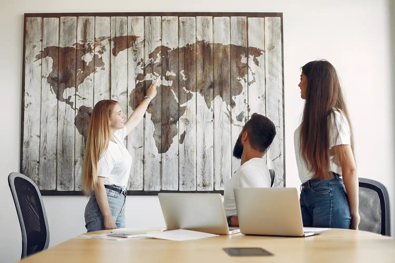 A group of people in an office looking at a world map.