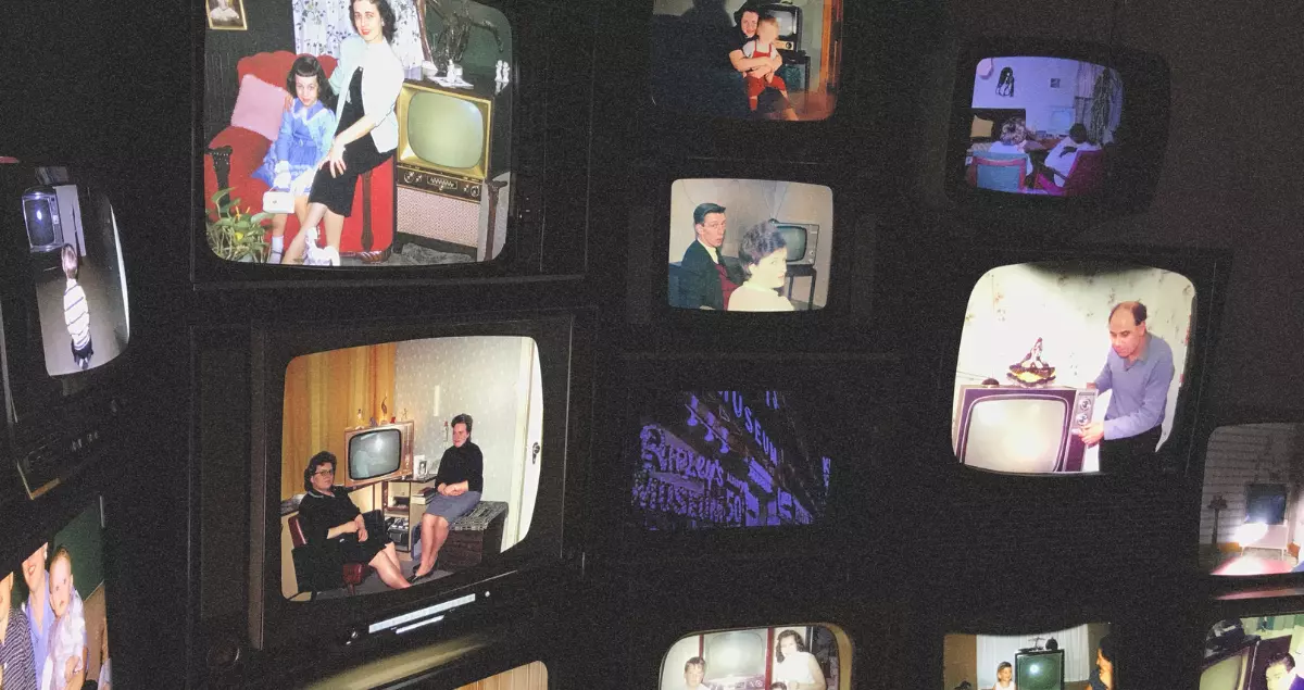 Multitud de televisores antiguos que muestran diversos contenidos relacionados con la familia.