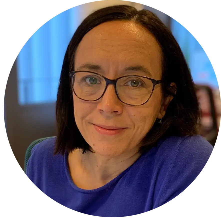 Fotografía de perfil de Maja Kurjak con el pelo oscuro hasta los hombros y gafas, vestida con un top azul y sonriendo ligeramente.