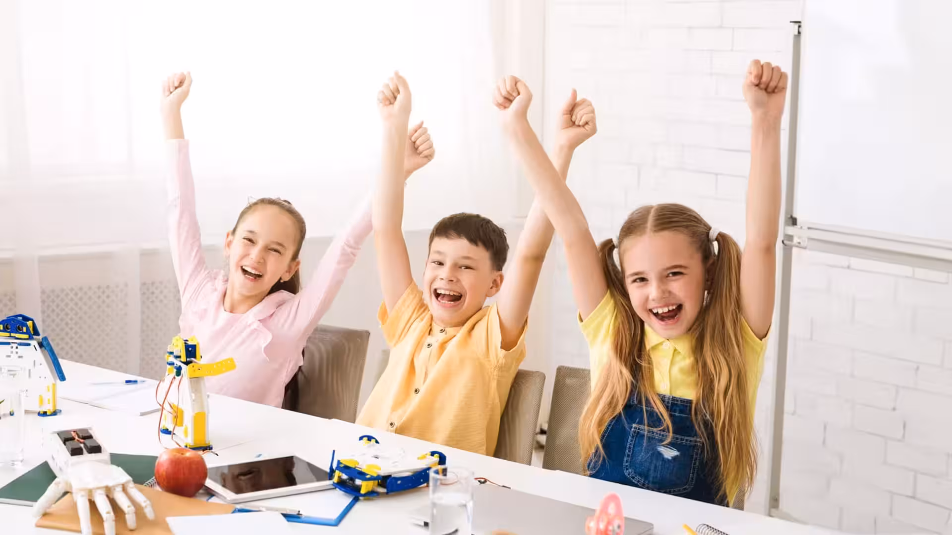 Tres niños entusiasmados celebran la finalización de un proyecto escolar.
