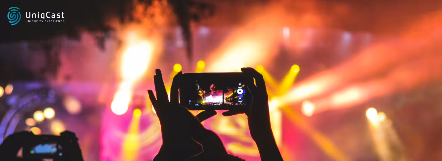 Una persona sostiene un teléfono celular para tomar una foto de un espectáculo de fuegos artificiales.