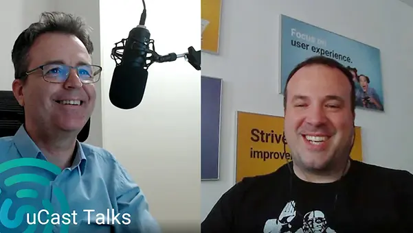 Dos hombres hablando alegremente delante de un micrófono.