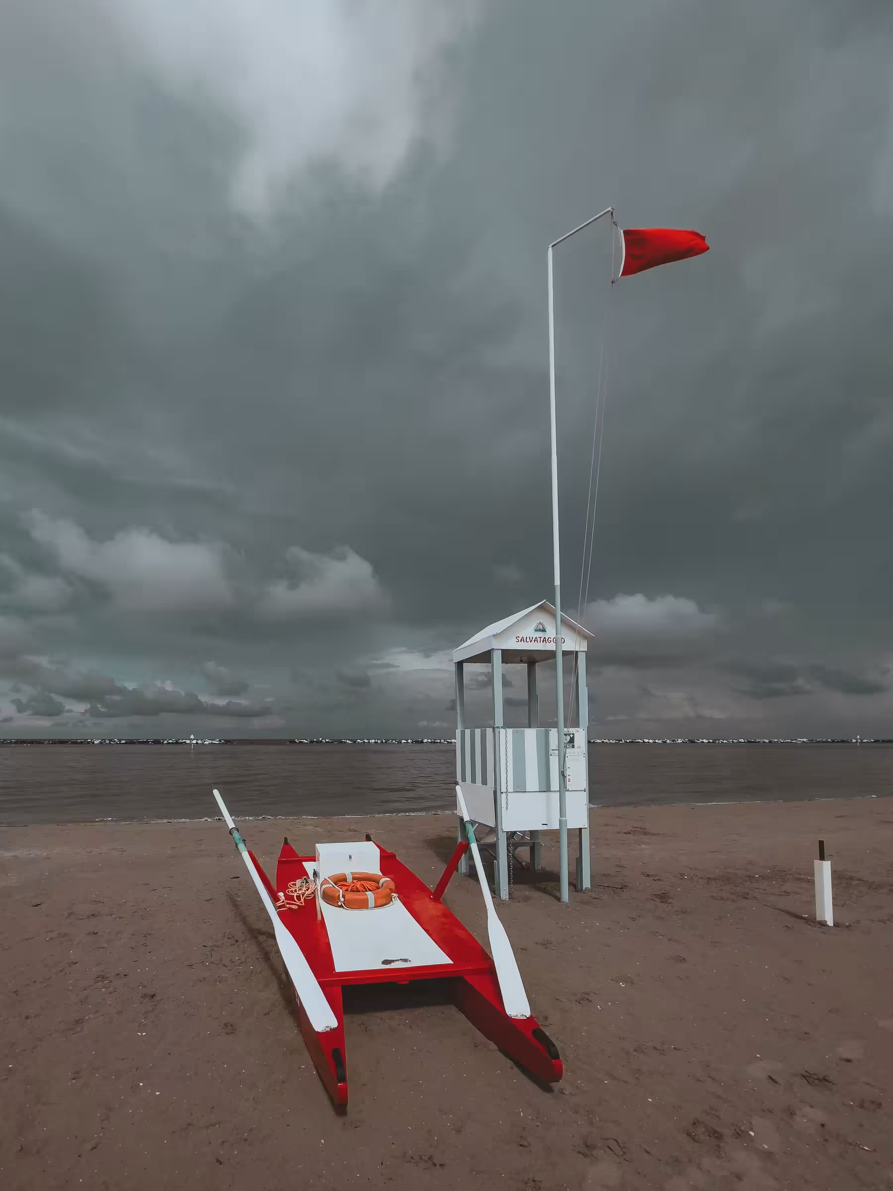 A lifeguard tower beside a red and white lifeguard stand on a sunny beach, with gentle waves in the background.
