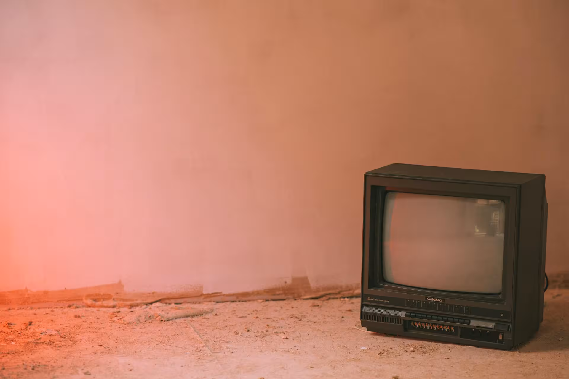 An antique television in a room, highlighted by a subtle red light creating a nostalgic atmosphere.