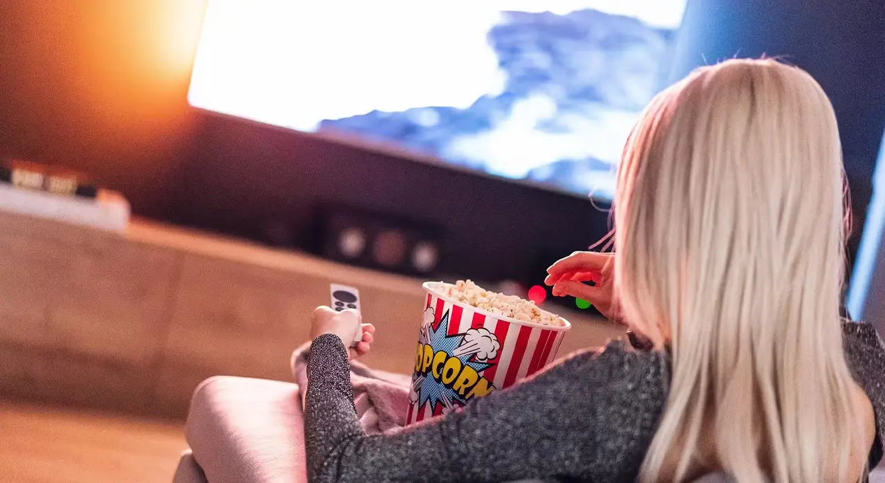  A woman sitting on a couch, enjoying popcorn while watching television
