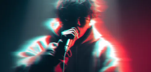 Artistic blurred image of a person holding a microphone close to their mouth with red and blue light effects.