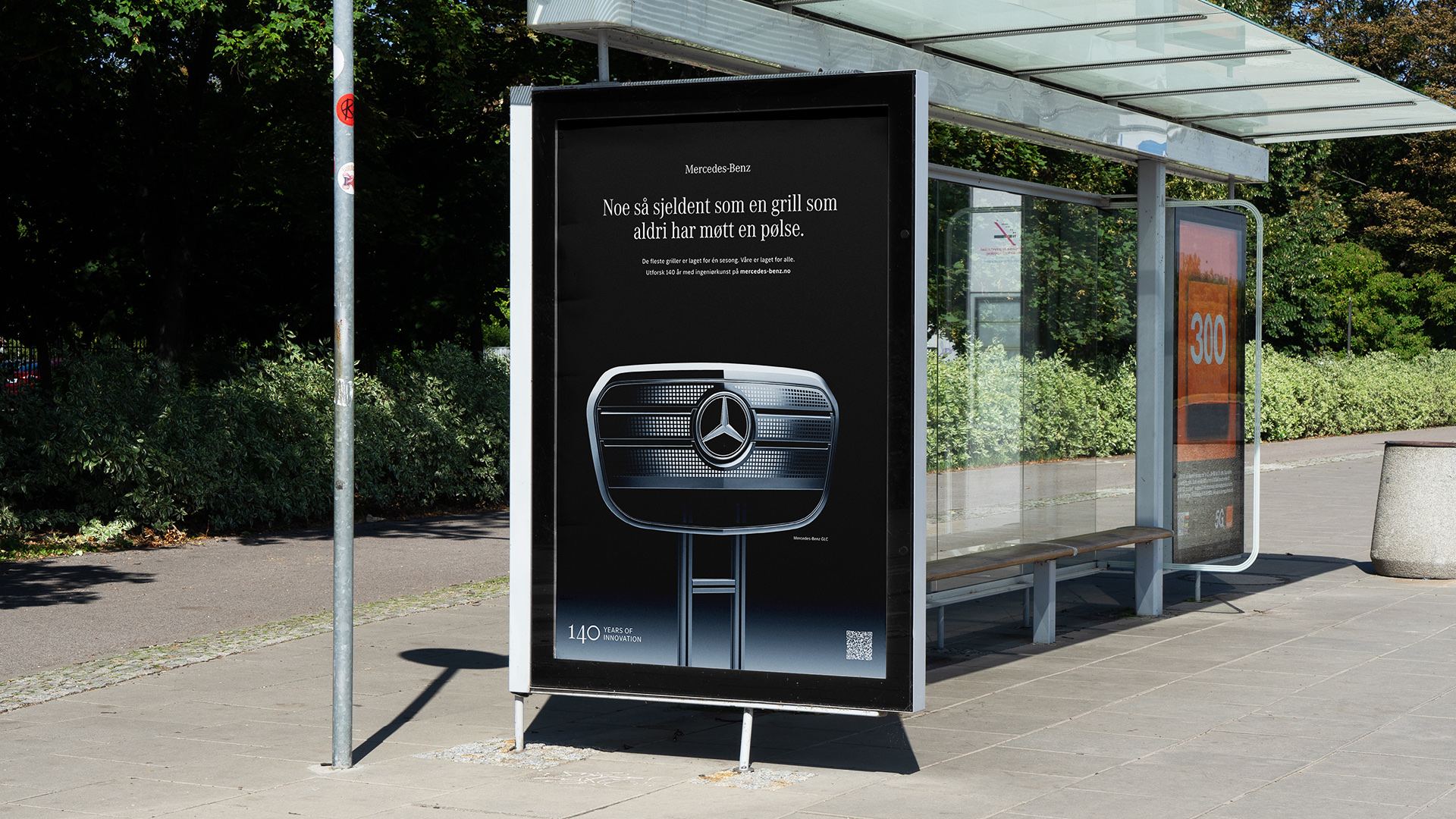 Adshel-plakat på busskur med Mercedes-Benz-grill på grillbein.