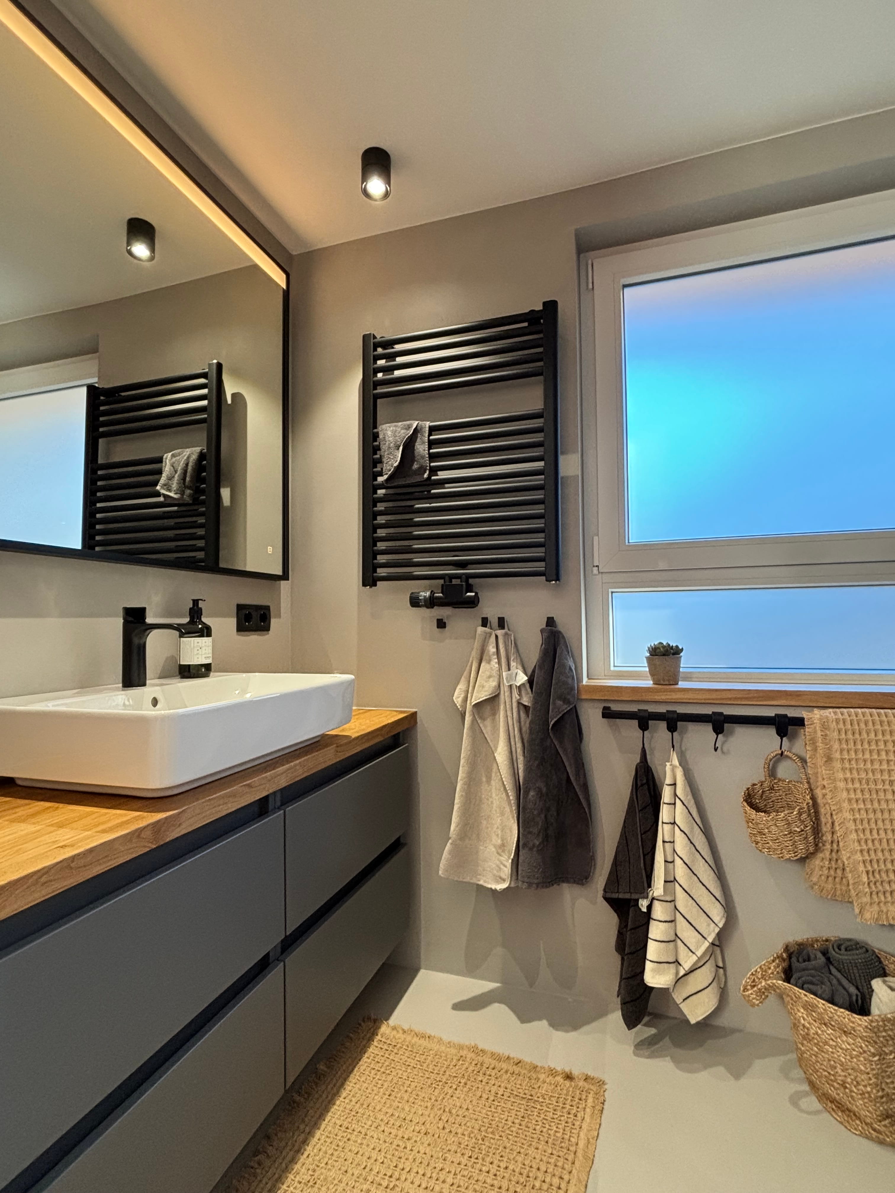 Modernes Badezimmer mit freistehender Badewanne, begehbarer Dusche mit Steinmauerfliesen und braunen Handtüchern auf weißem Handtuchwärmer.